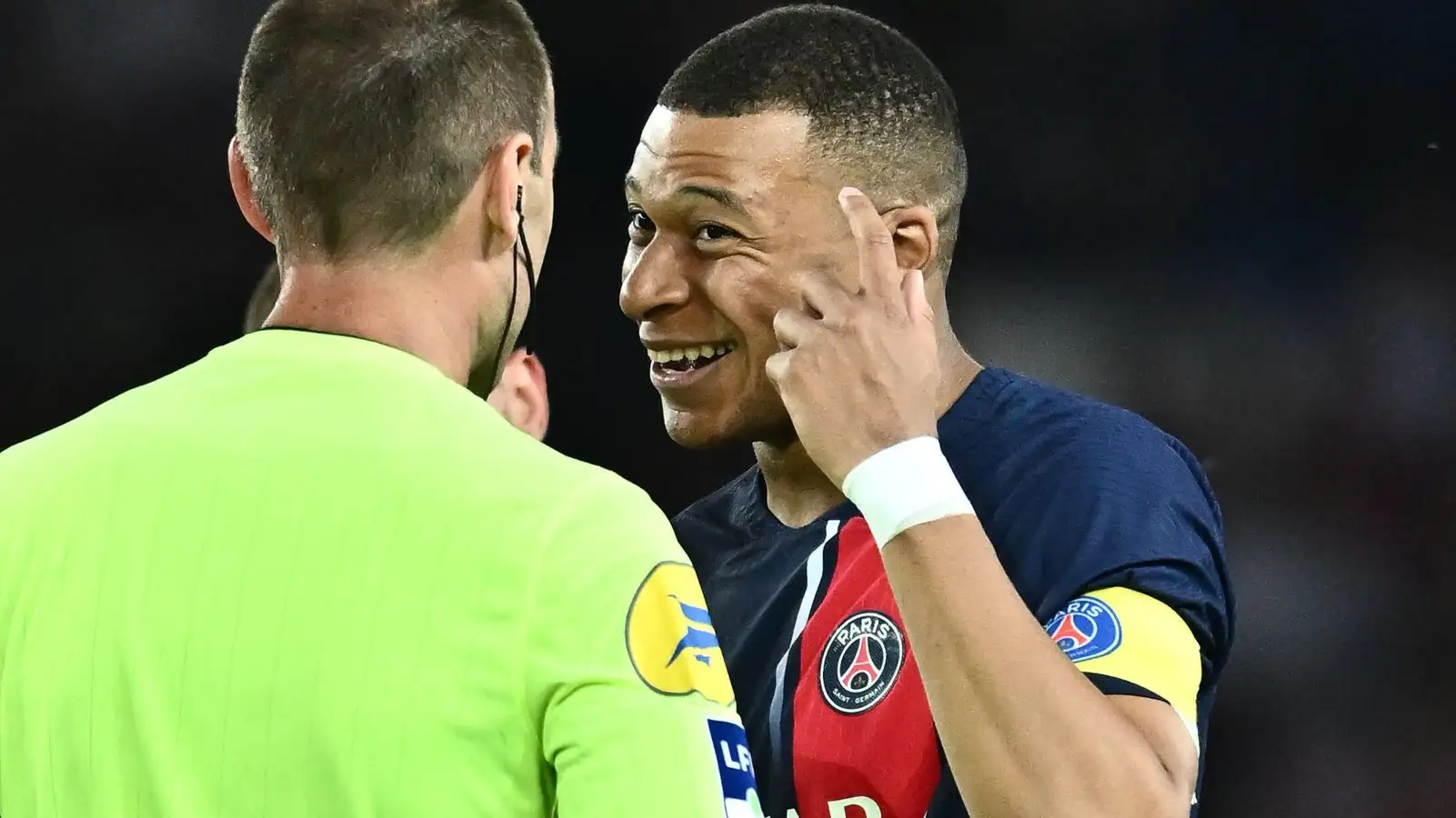 Kylian Mbappe chats with an official during a PSG game.