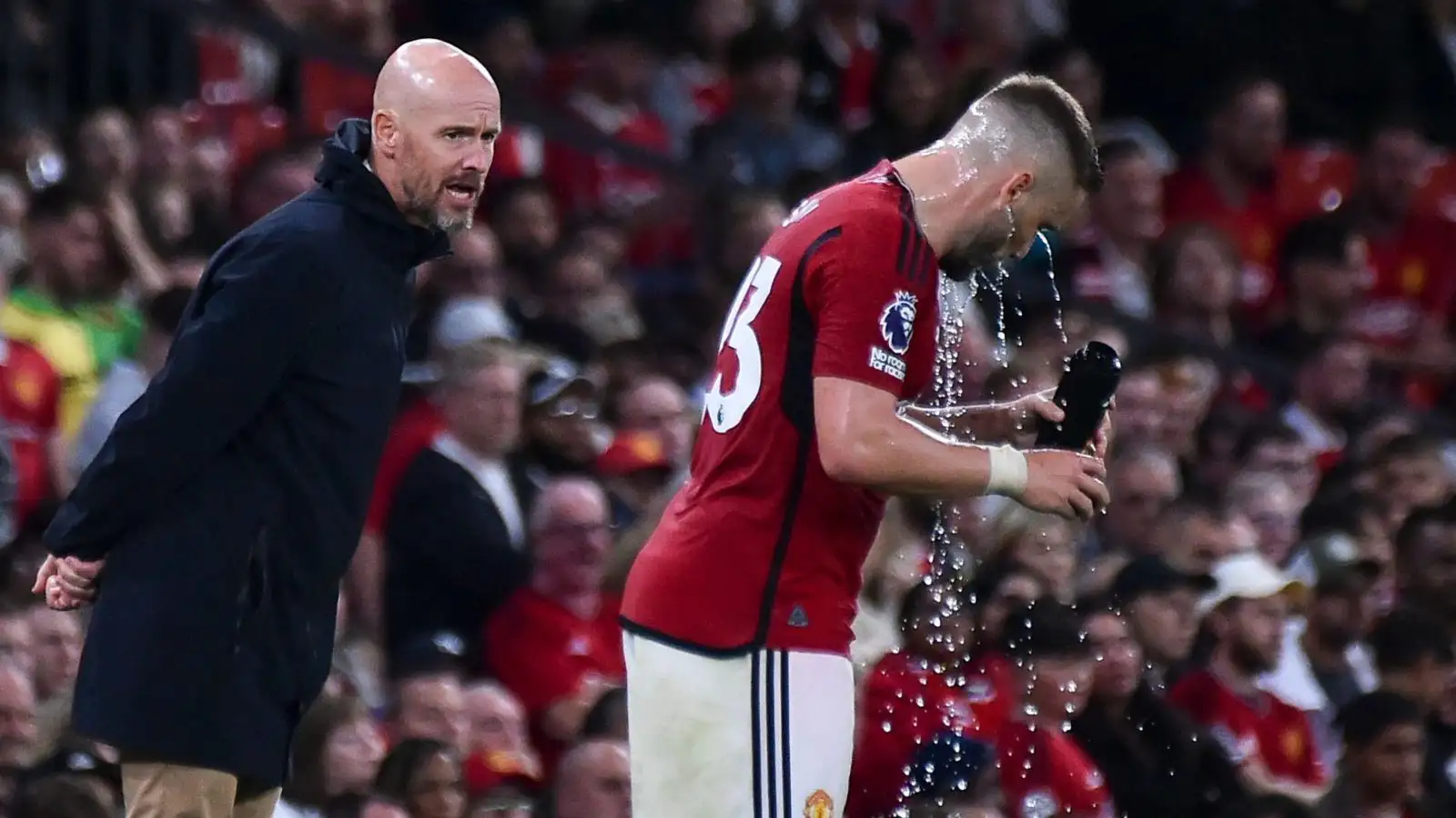 Manchester United manager Erik ten Hag gives instructions to a drenched Luke Shaw.