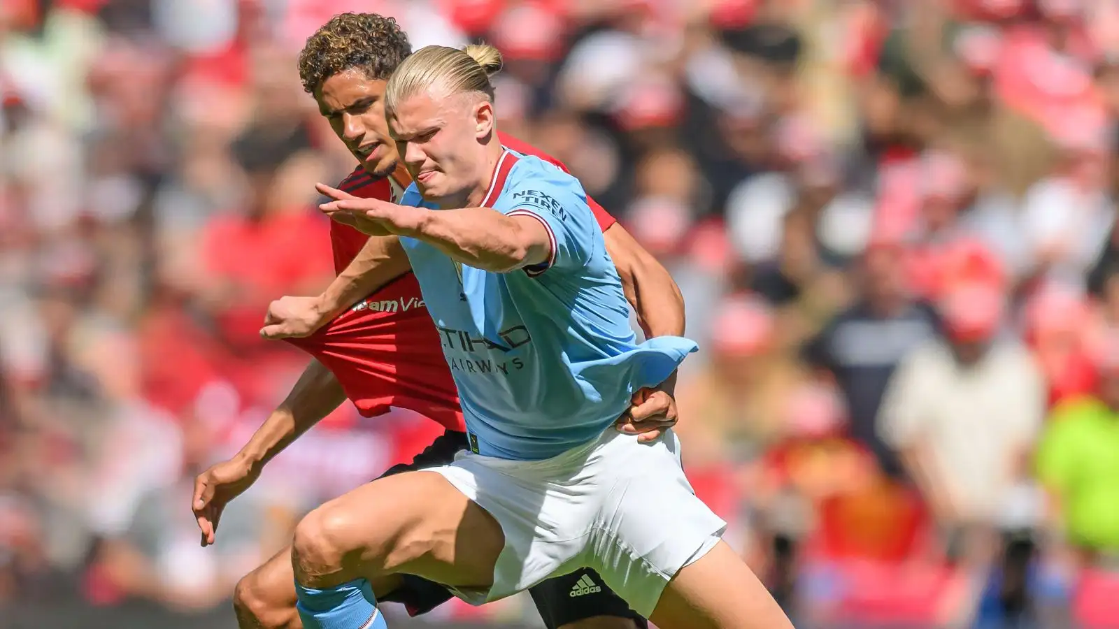 Man Utd defender Raphael Varane fights Erling Haaland for the sphere.