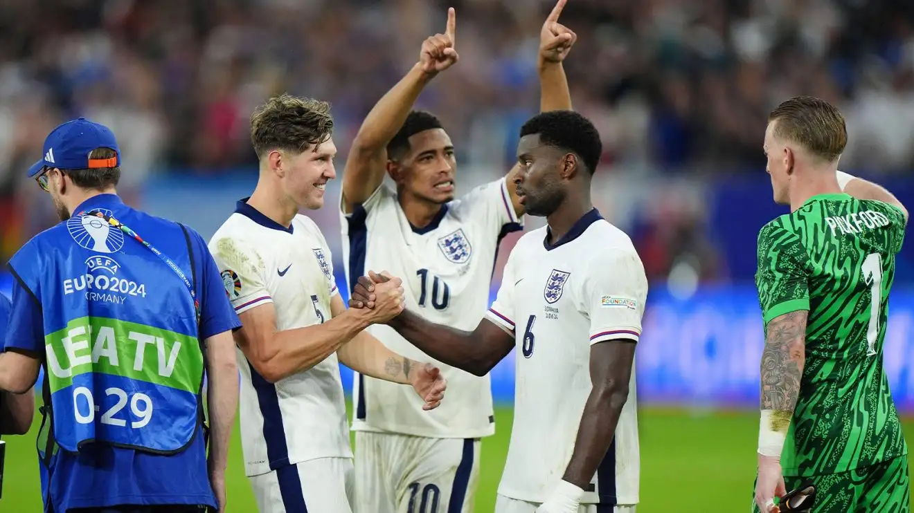 John Stones shares a celebratory over-hand handshake with Marc Guehi at Euro 2024 as Jude Bellingham and Jordan Pickford also celebrate in the background