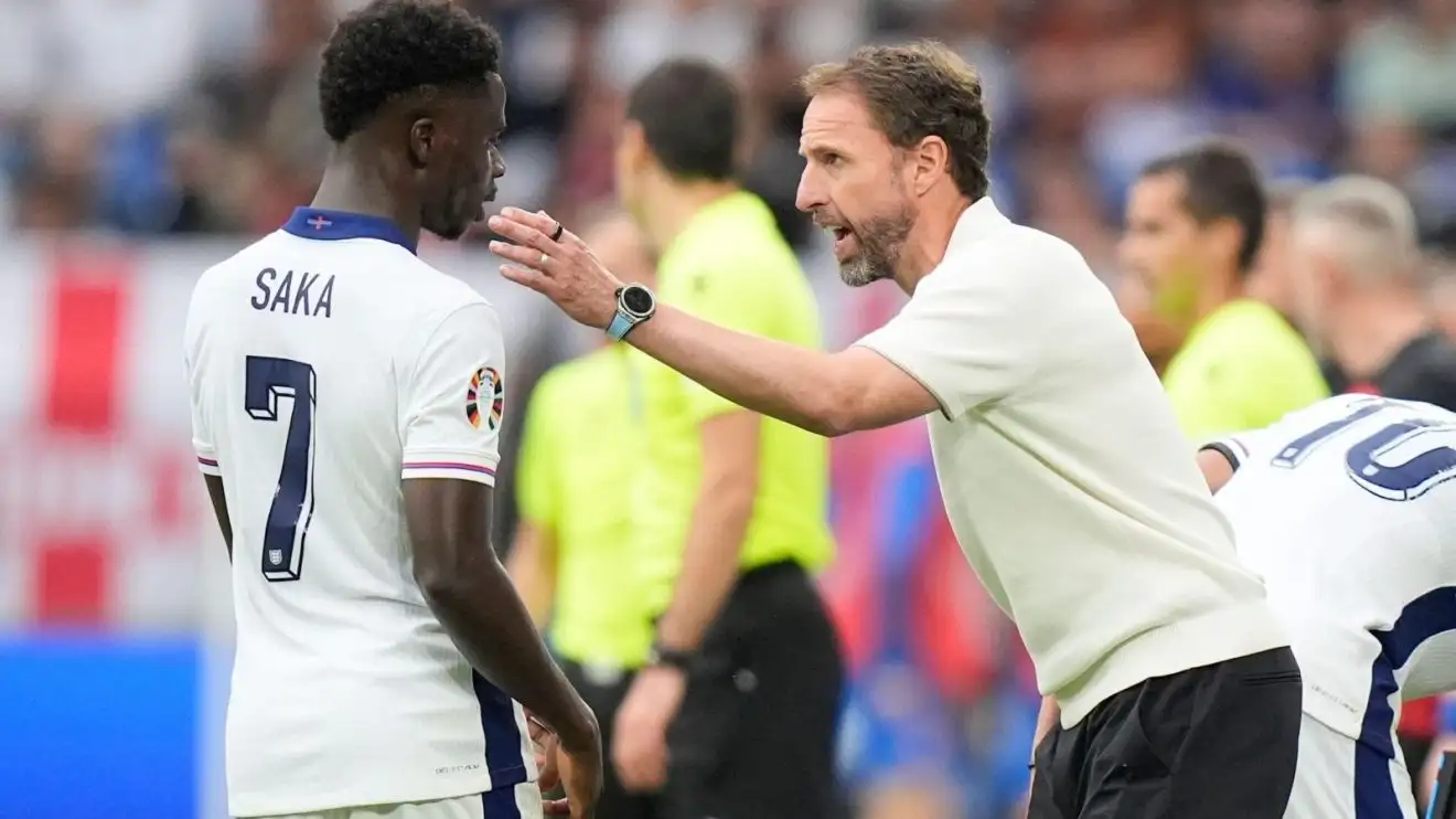 England employer Gareth Southgate confers instructions to Bukayo Saka