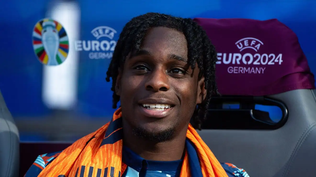 Jeremie Frimpong has a significant donned smile on his face while resting on the bench at Euro 2024