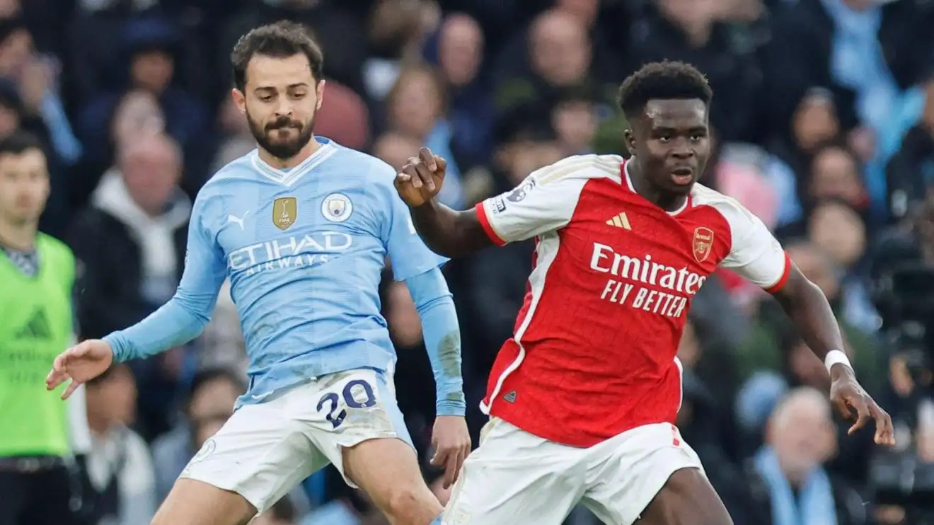 Manchester City player Bernardo Silva and Arsenal forward Bukayo Saka compete for the ball
