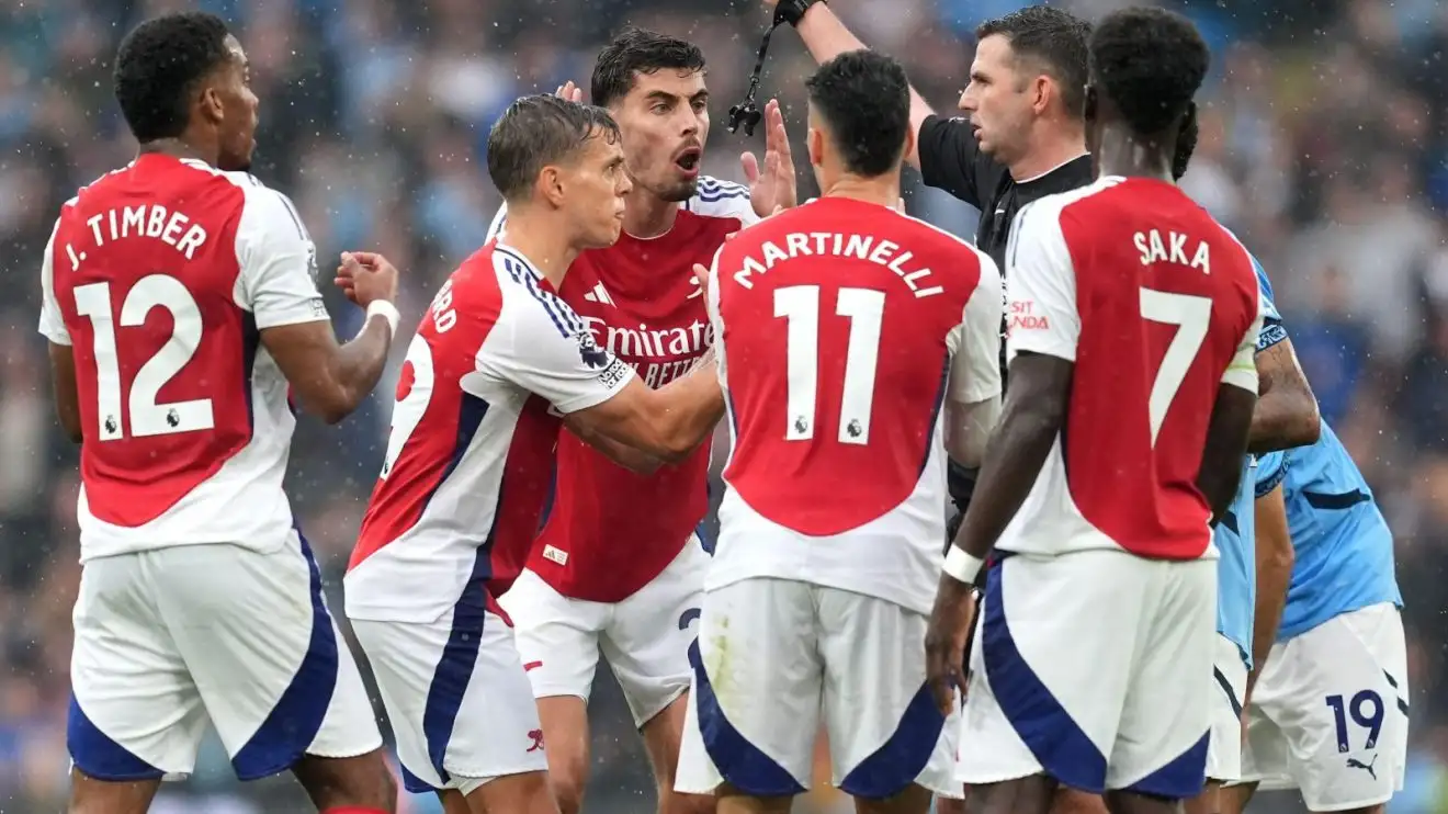 Arsenal encircle Michael Oliver after Leandro Trossard's red card.