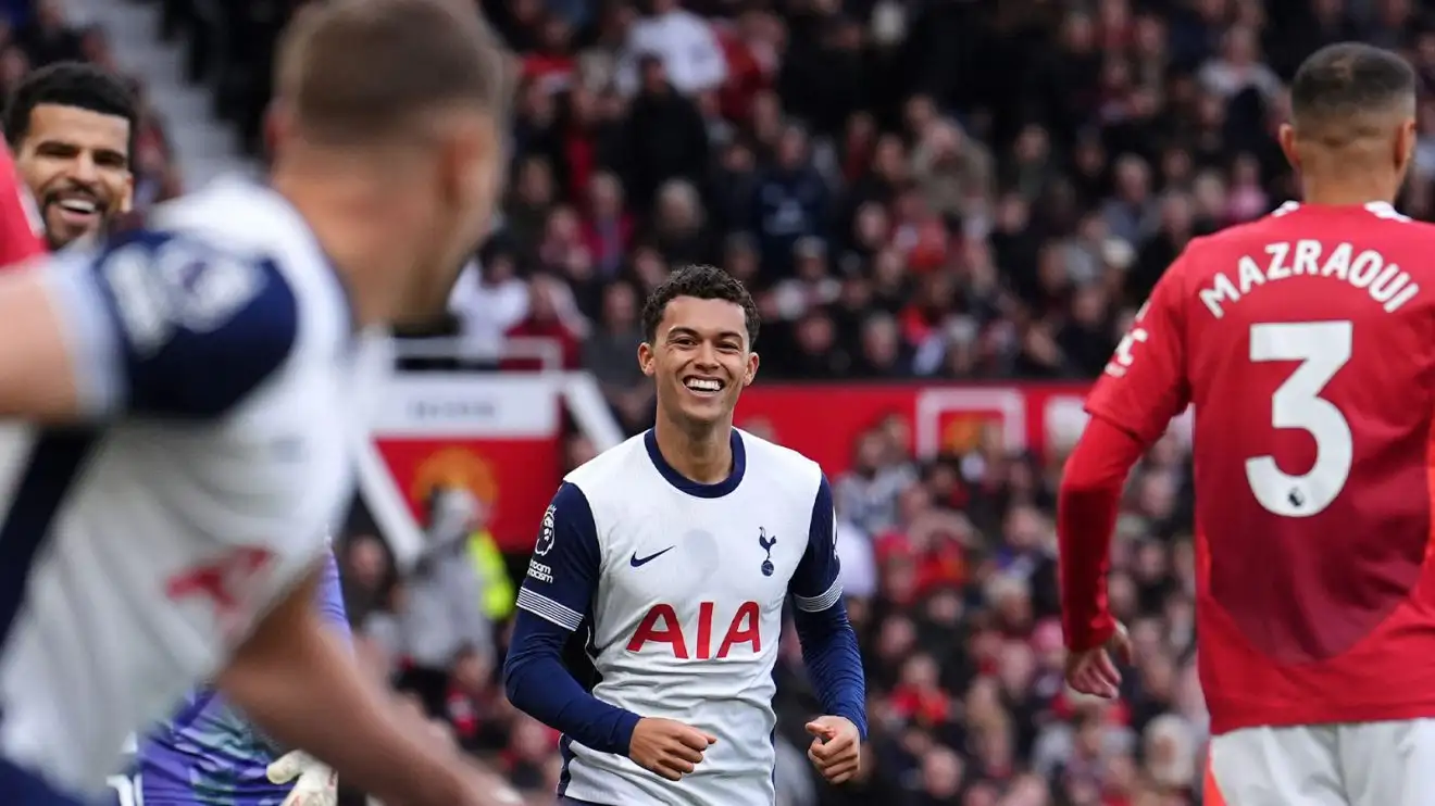 Tottenham's Brennan Johnson smiles broadly, as does teammate Dominic Solanke in the background, while Manchester United's Noussair Mazraoui manages to look dejected despite having his back to the camera