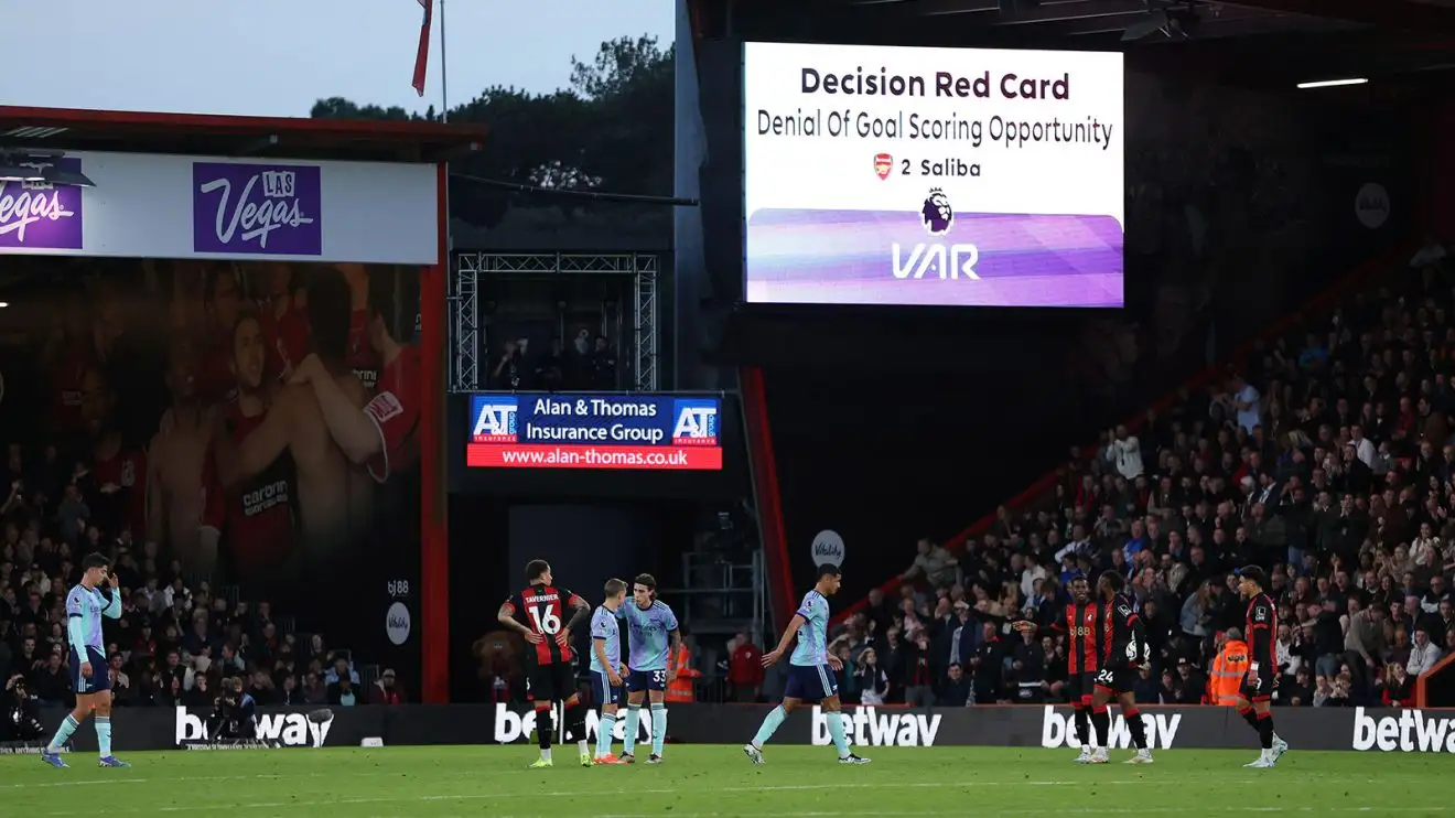 William Saliba departs the field following his dismissal, with the big screen behind him confirming his red card decision delivered following a video review