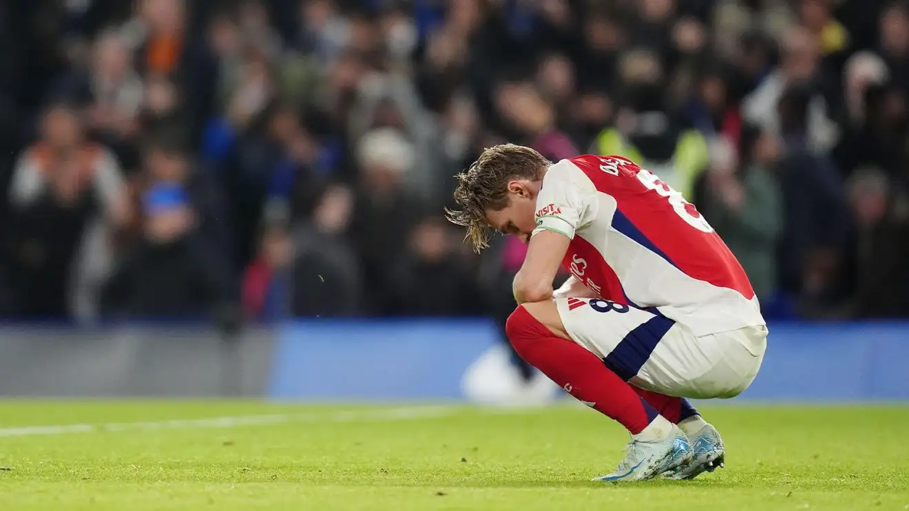 Martin Odegaard squats in disappointment on the pitch at Stamford Bridge