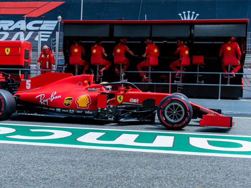 Sebastian Vettel drives past Ferrari pit wall