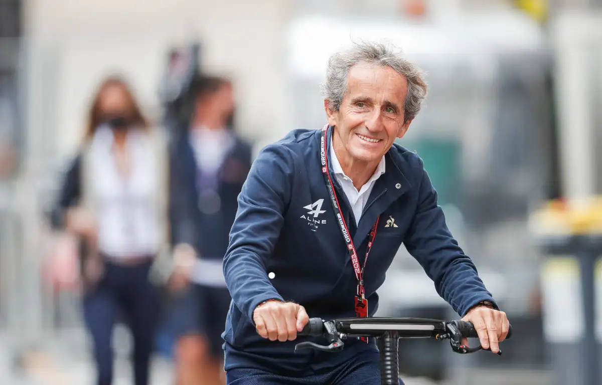 Alain Prost cycles into the paddock.