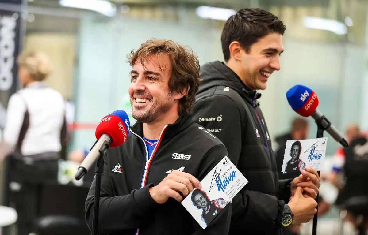 Fernando Alonso and Esteban Ocon stand back-to-back. Brazil November 2021.