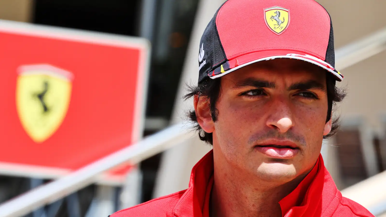 Carlos Sainz looking serious, Ferrari logo in the background. Bahrain March 2022