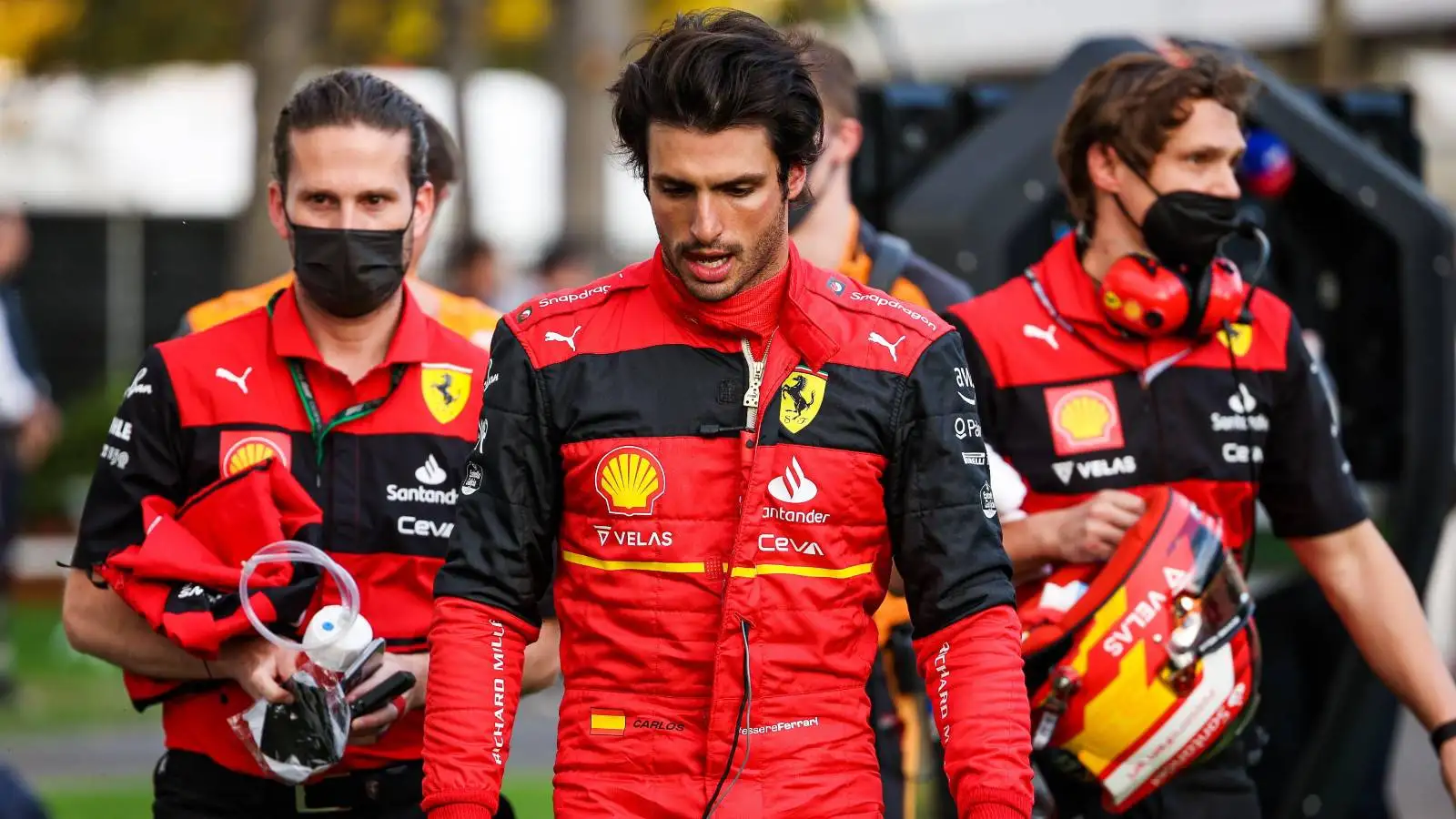 Carlos Sainz walks head down with Ferrari team members. Australia, April 2022.