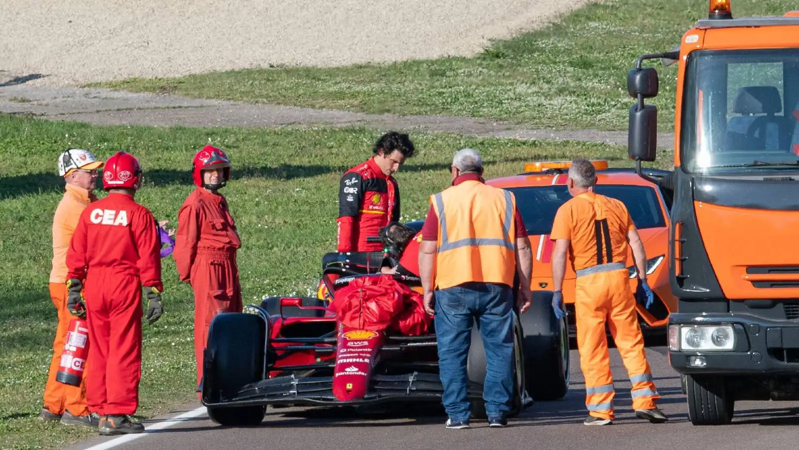 Carlos Sainz stands by stricken Ferrari. Imola April 2024.