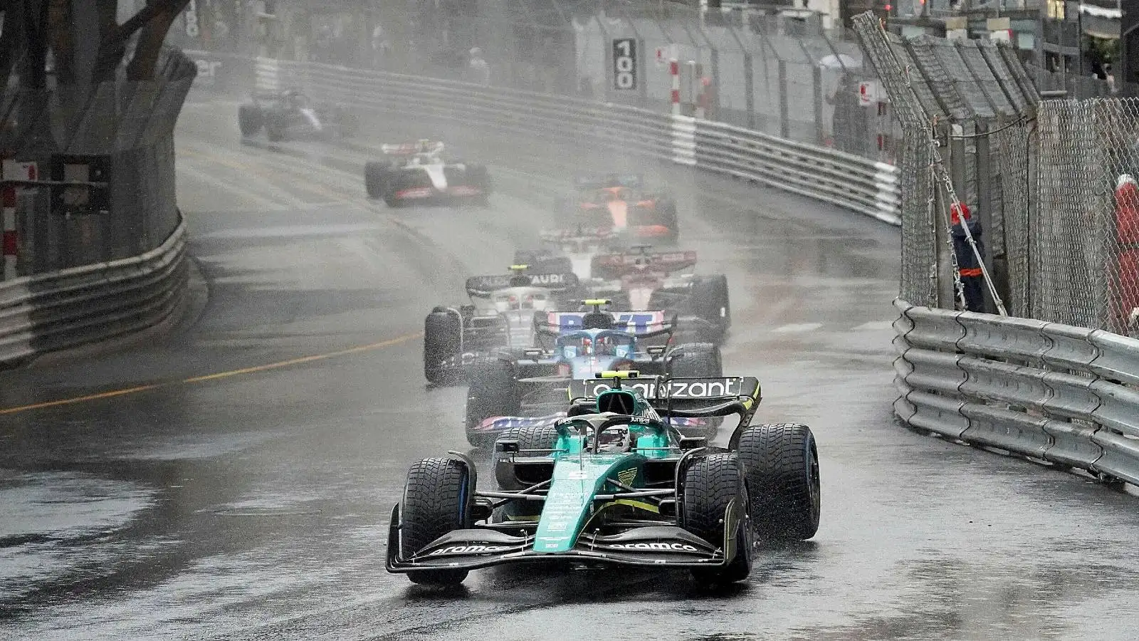 Cars follow Sebastian Vettel, Aston Martin, in the wet. Monaco, May 2022.