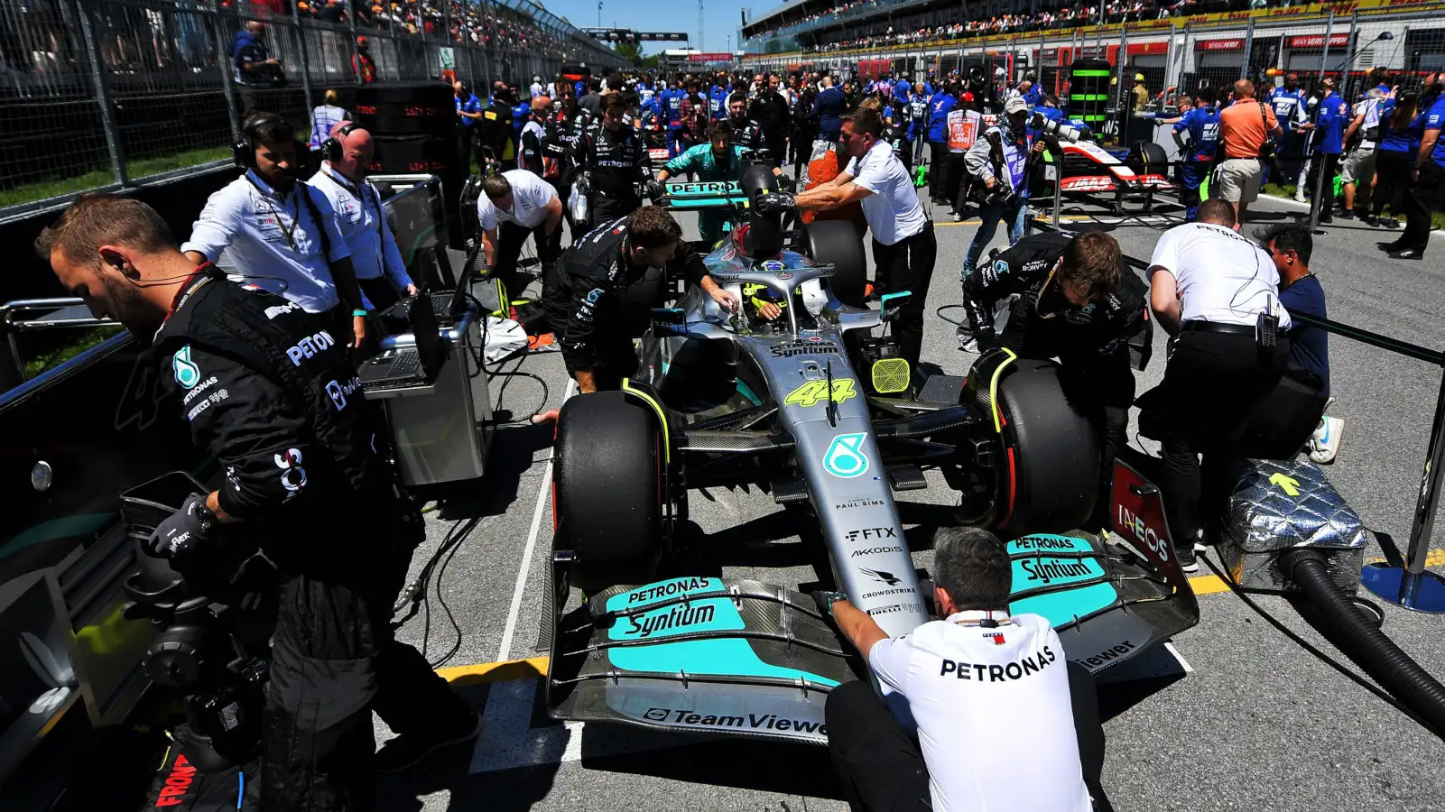 Lewis Hamilton sits in his car on the grid, mechanics present. Montreal June 2022