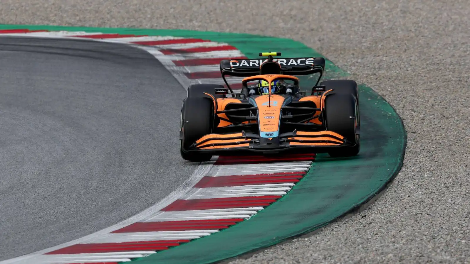 Lando Norris, McLaren, takes plenty of kerb. Austria, July 2022.