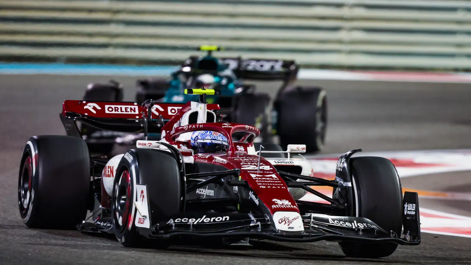 Guanyu Zhou running ahead of Sebastian Vettel under lights. Abu Dhabi November 20222