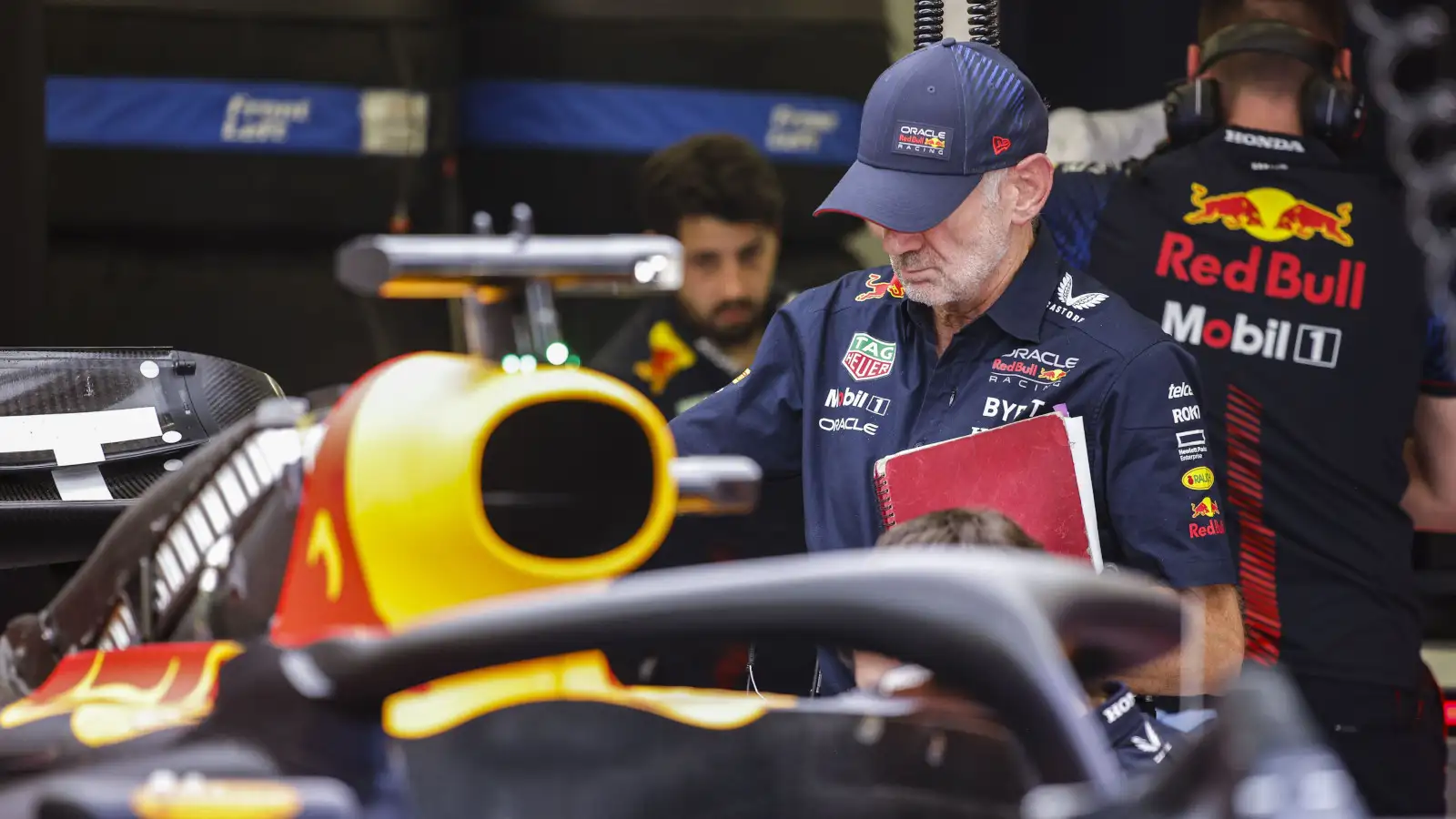 Adrian Newey inspecting the RB19 with his notebook in hand.
