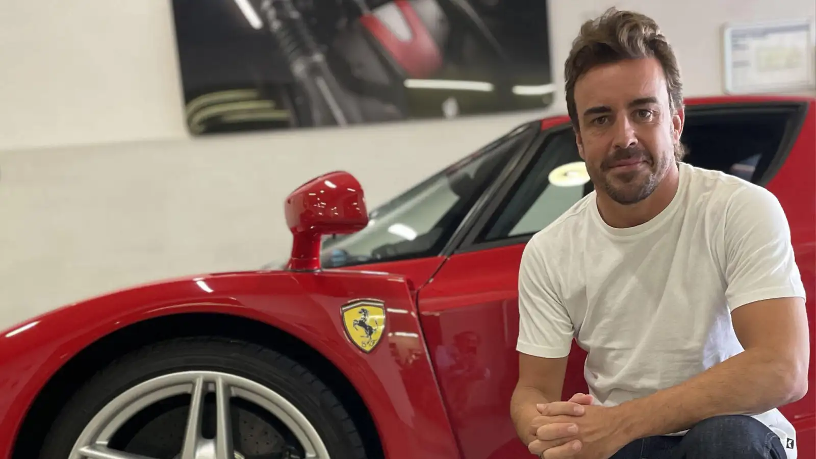 Fernando Alonso poses with the Ferrari Enzo road car he has put up for auction. May, 2023.