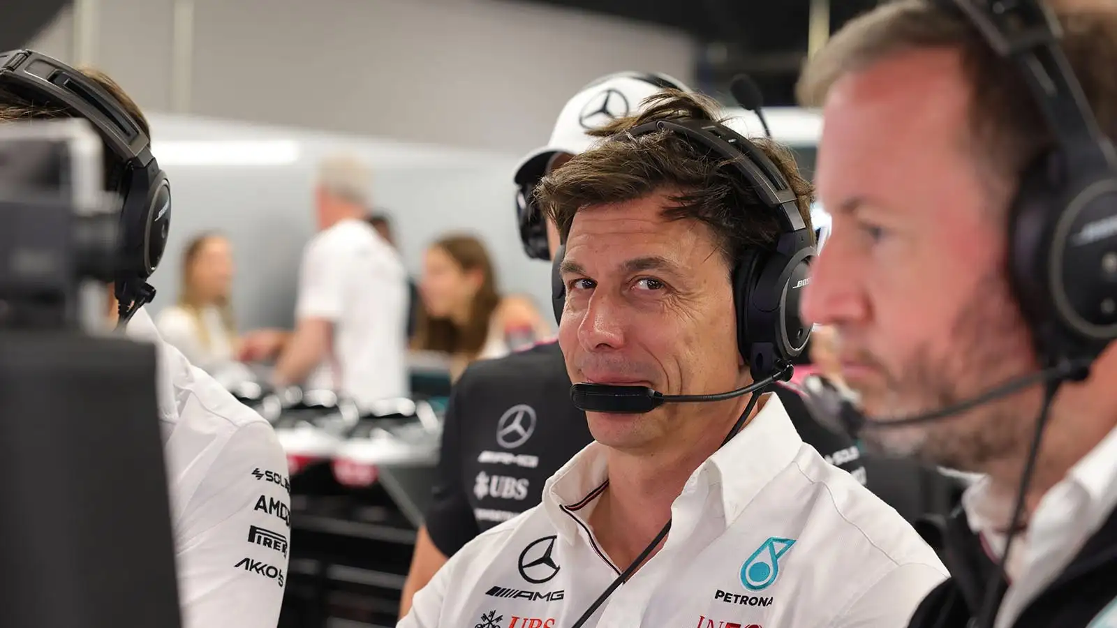 Toto Wolff smiles towards the camera with his headphones on.