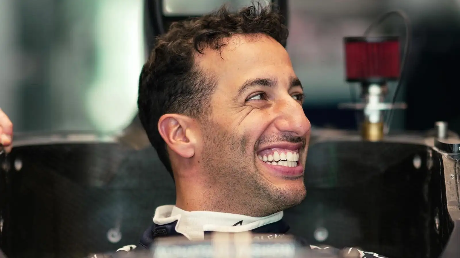 Daniel Ricciardo smiling during a seat fit. July 2023.