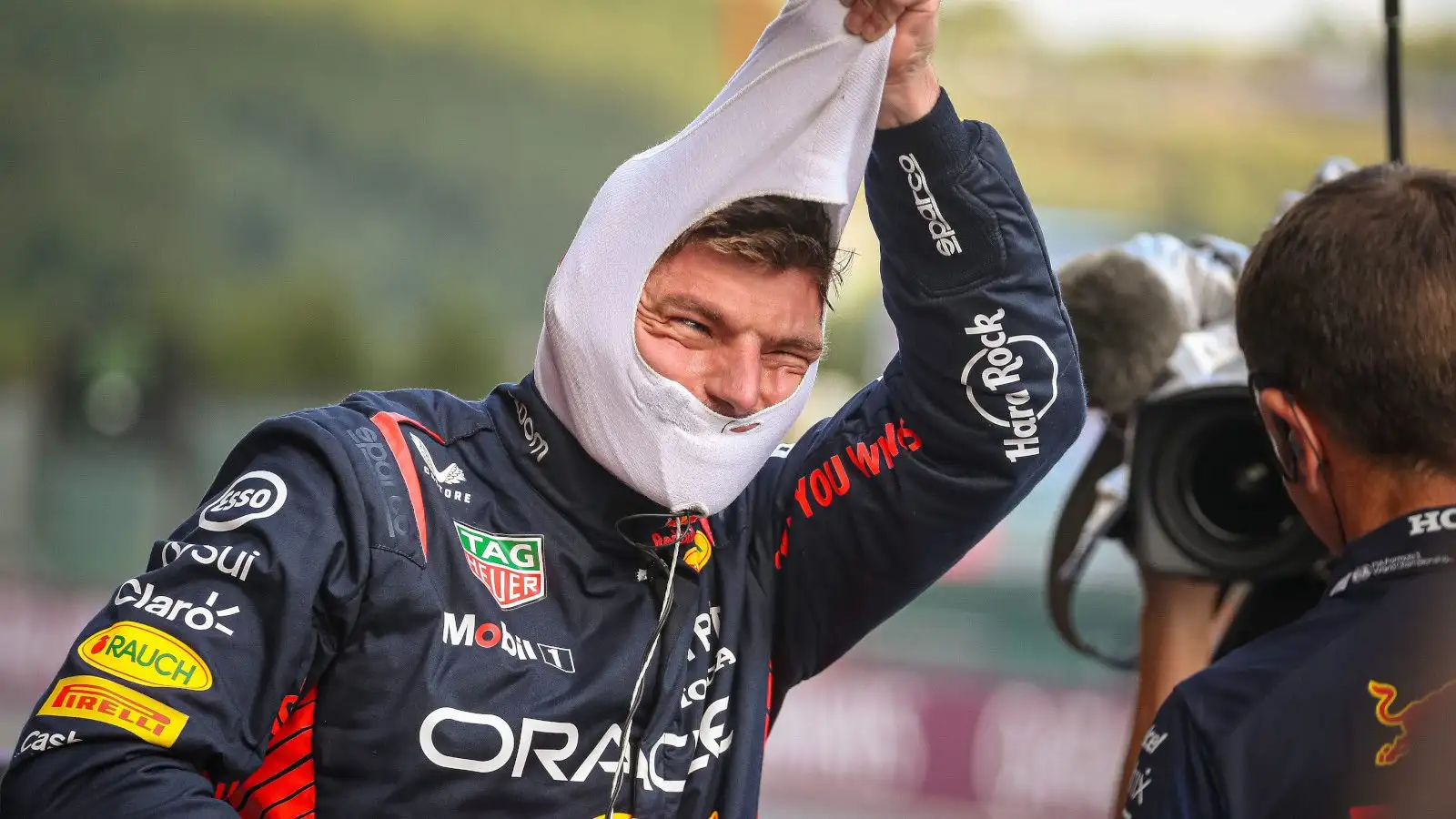 Max Verstappen smiling as he pulls off his fireproofs.