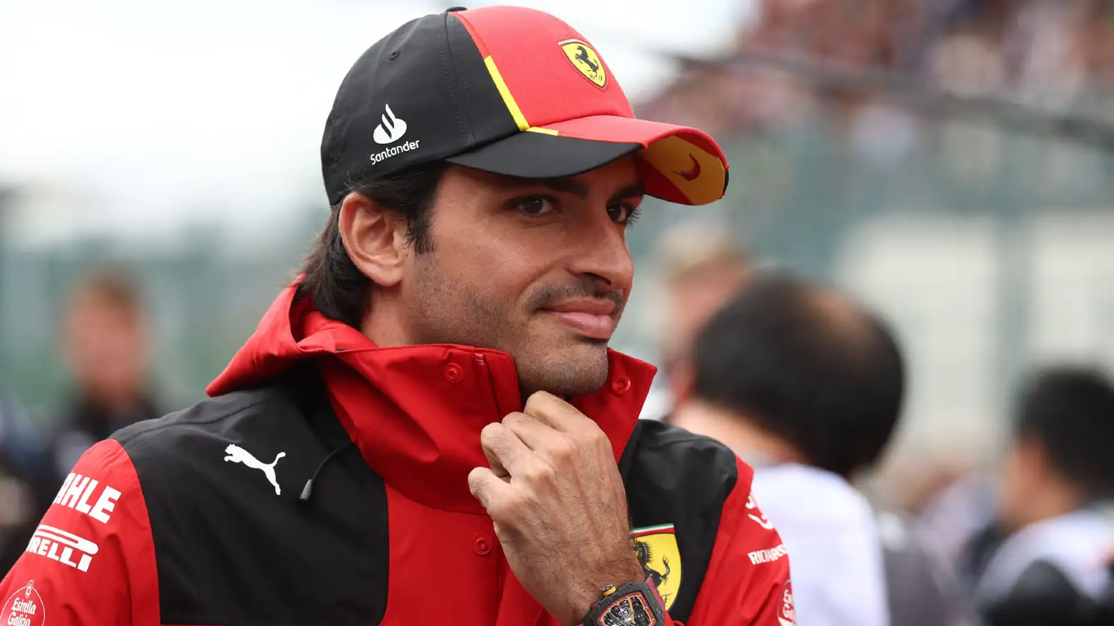 2023年比利时草nd Prix: Ferrari's Carlos Sainz adjusts his jacket against the windy conditions at Spa-Francorchamps.