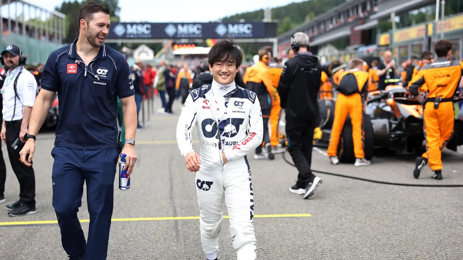 AlphaTauri's Yuki Tsunoda smiling as he walks down the grid.