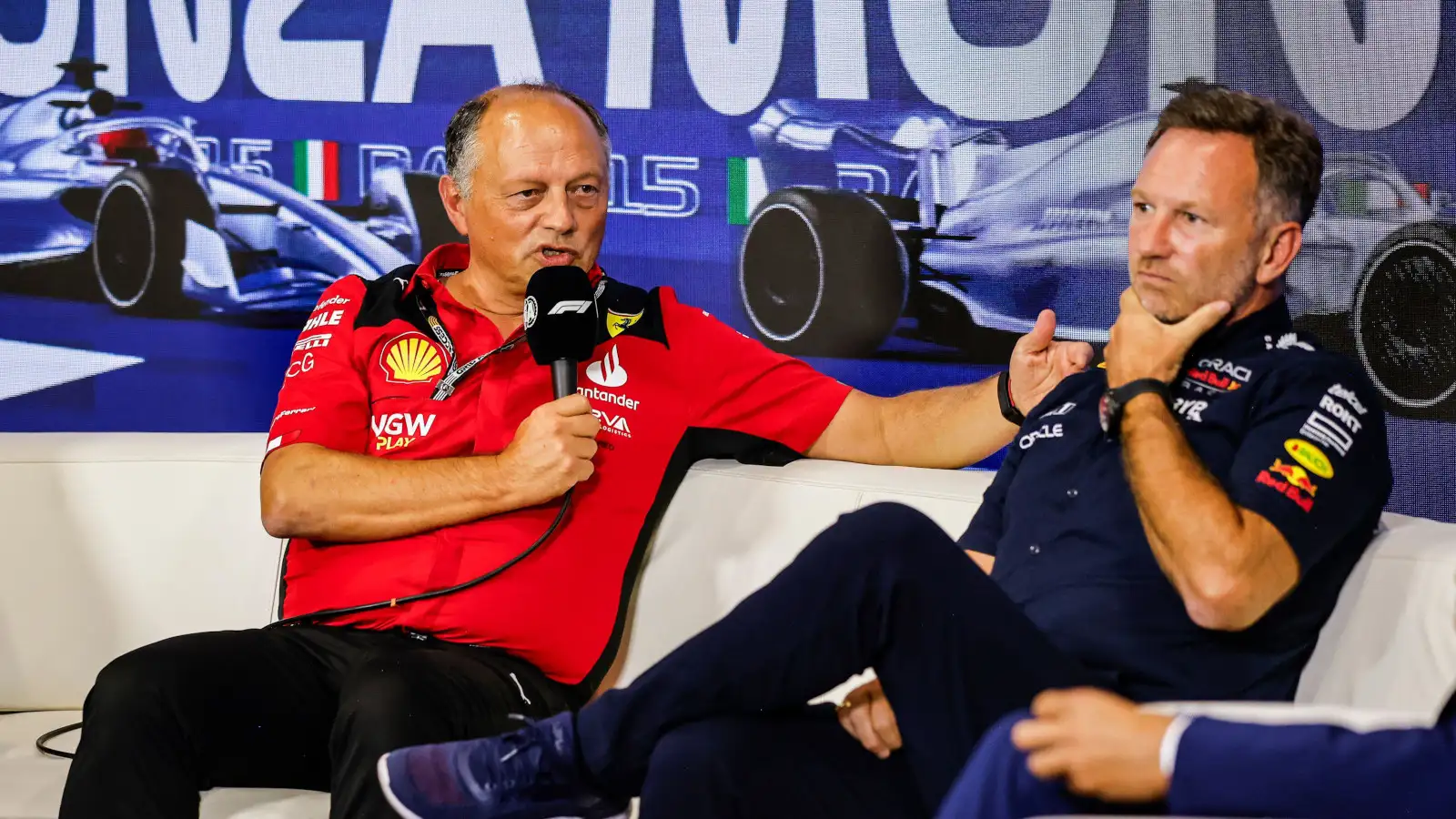 Ferrari team boss Fred Vasseur explains during a press conference while Christian Horner ponders.