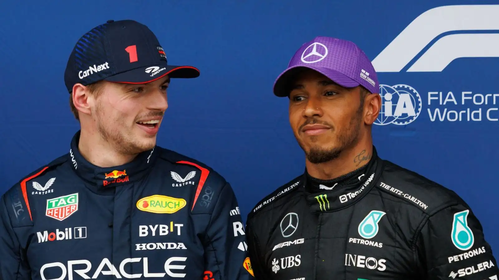Red Bull driver Max Verstappen laughs as Mercedes rival Lewis Hamilton looks on.