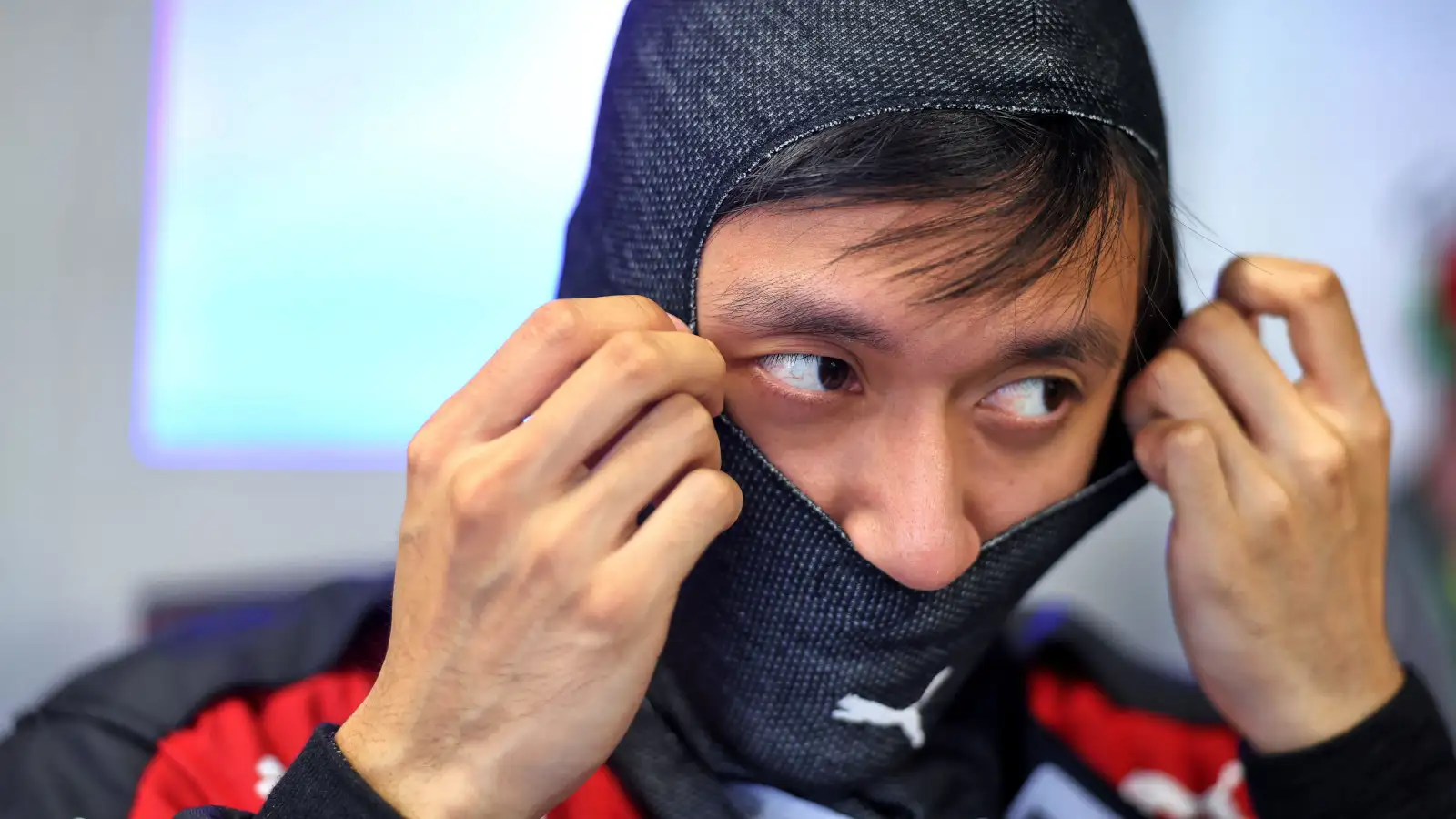 Alfa Romeo driver Zhou Guanyu putting on his fireproofs before a session.