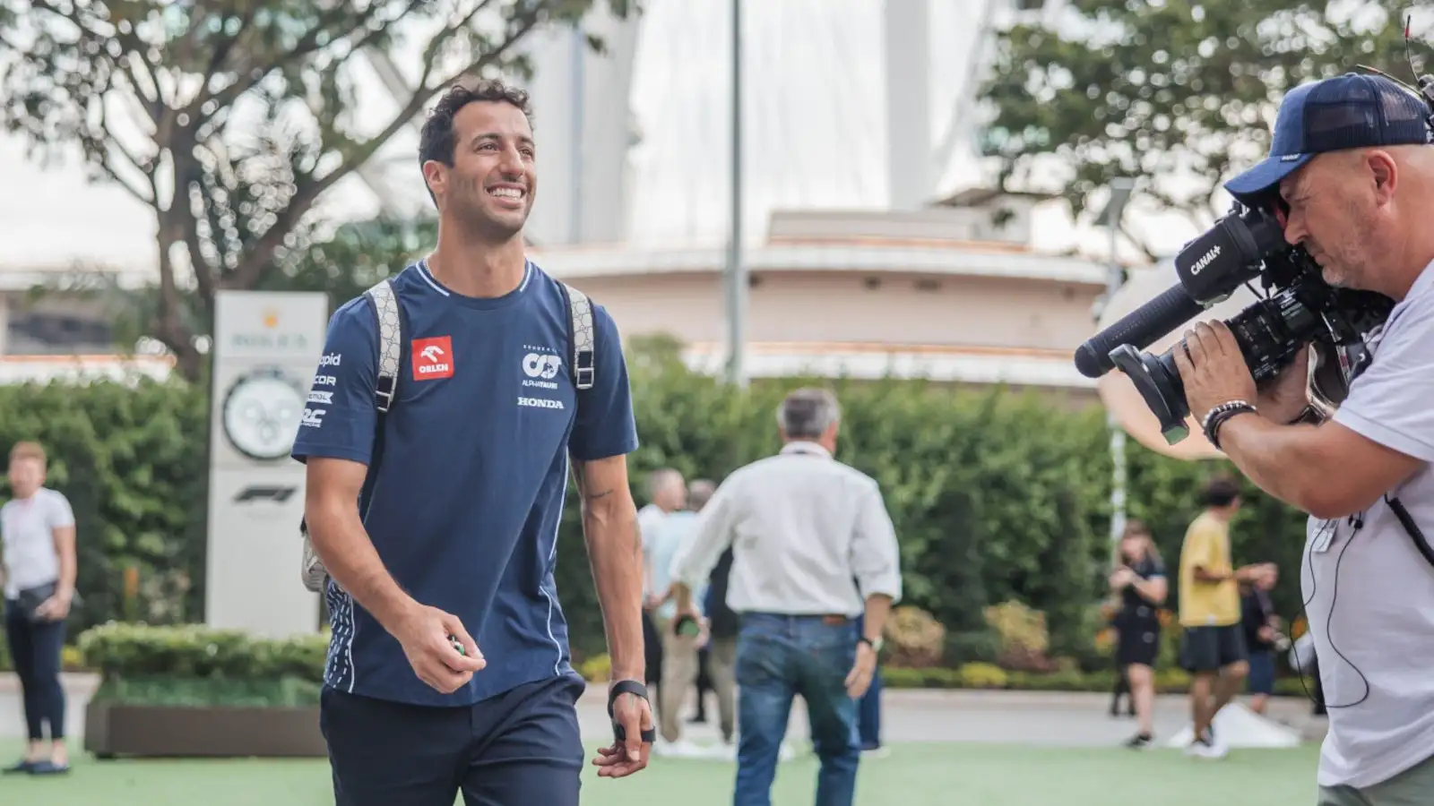 AlphaTauri driver Daniel Ricciardo walks in the paddock with his left hand strapped.