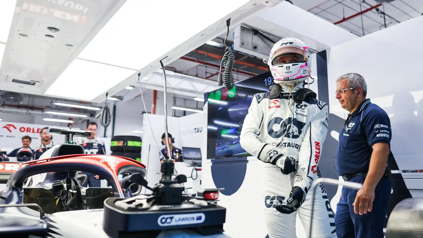 Liam Lawson standing next to his AT04 in the AlphaTauri garage.