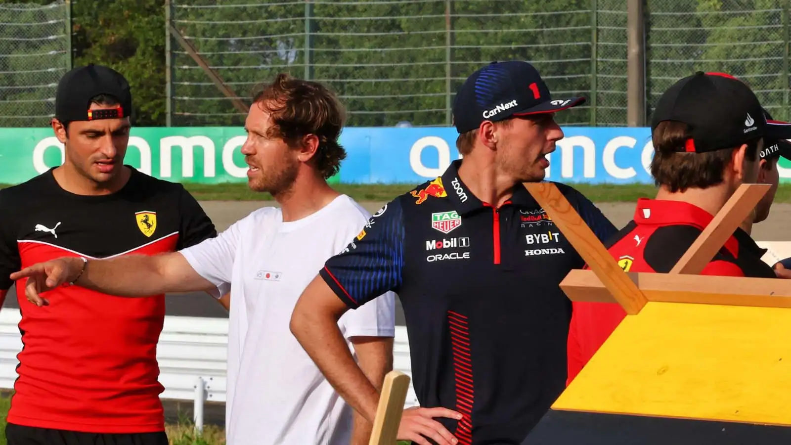 Sebastian Vettel stands behind Max Verstappen.