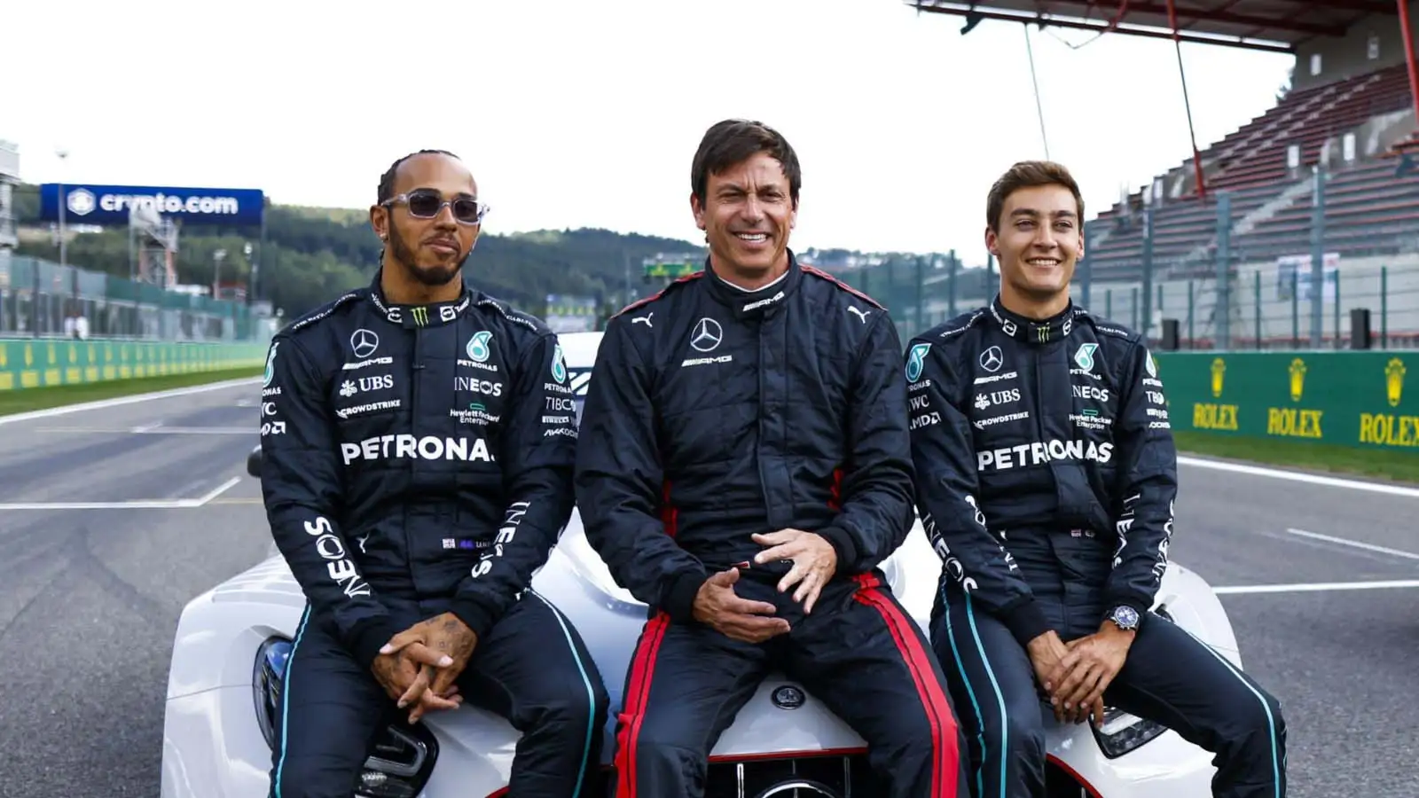 Lewis Hamilton, Toto Wolff and George Russell sit on a Mercedes bonnet.