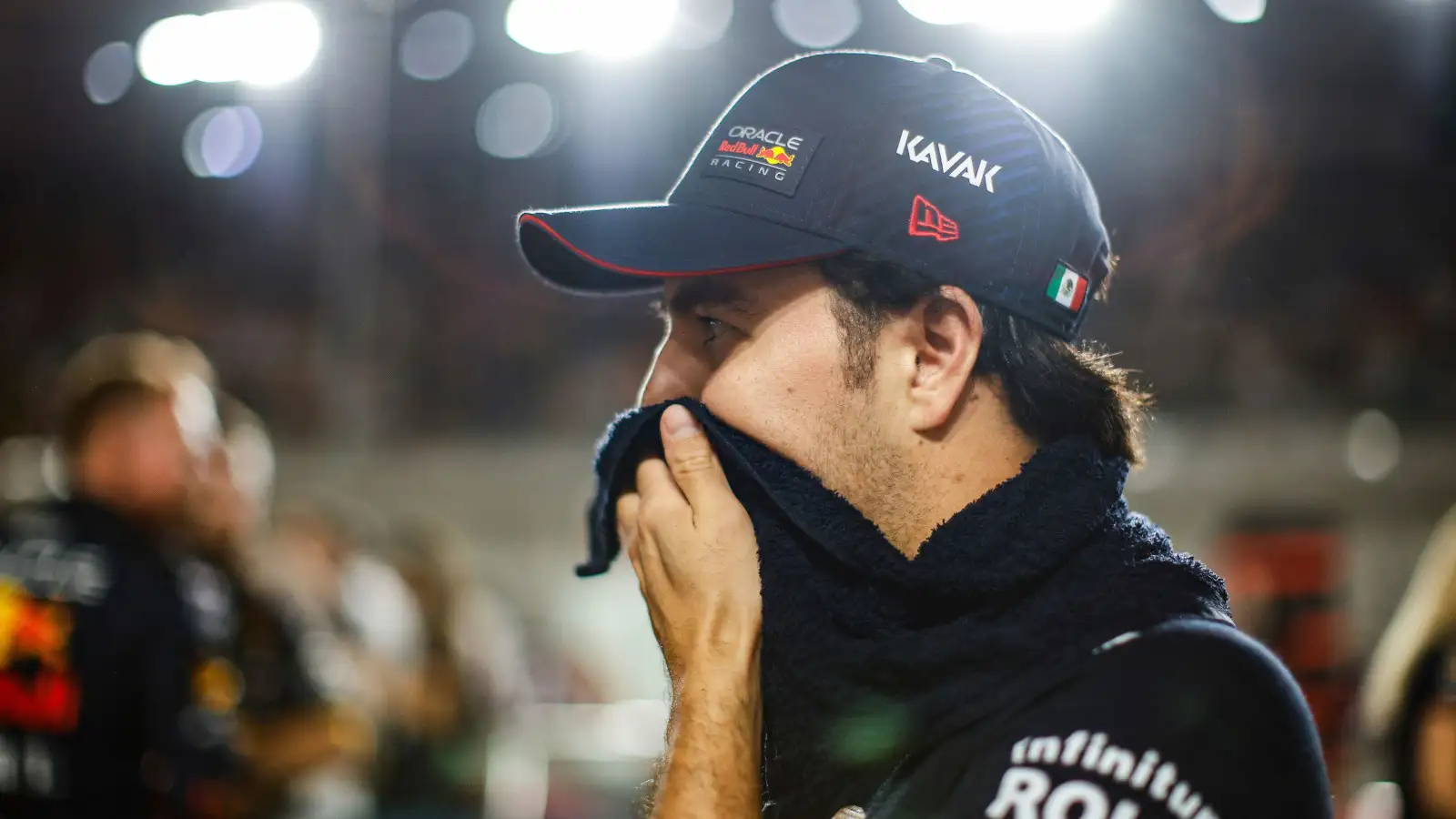 Red Bull driver Sergio Perez holds a towel to his face under the lights in Qatar.