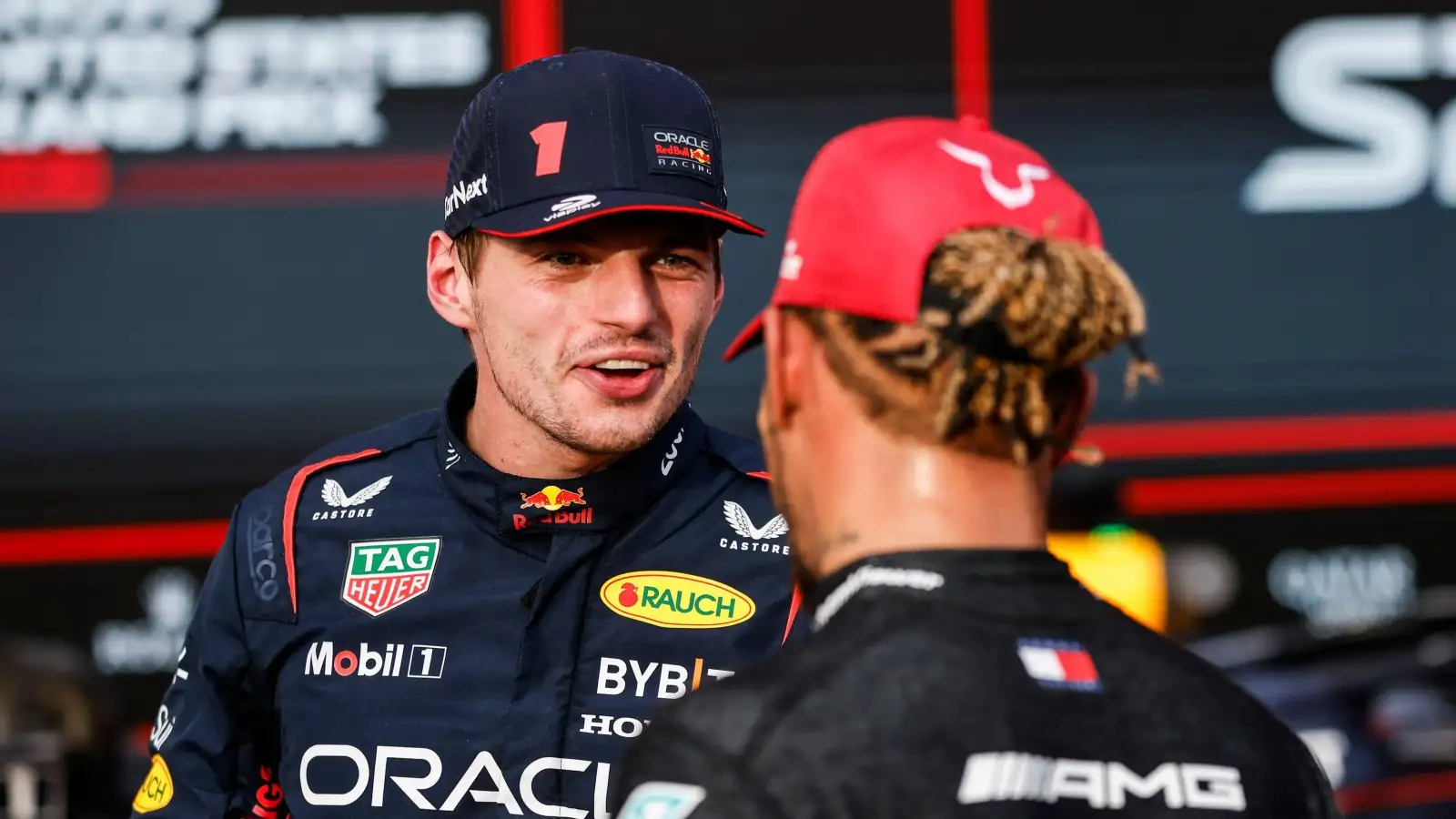Red Bull driver Max Verstappen smiles and talks to Mercedes driver Lewis Hamilton.