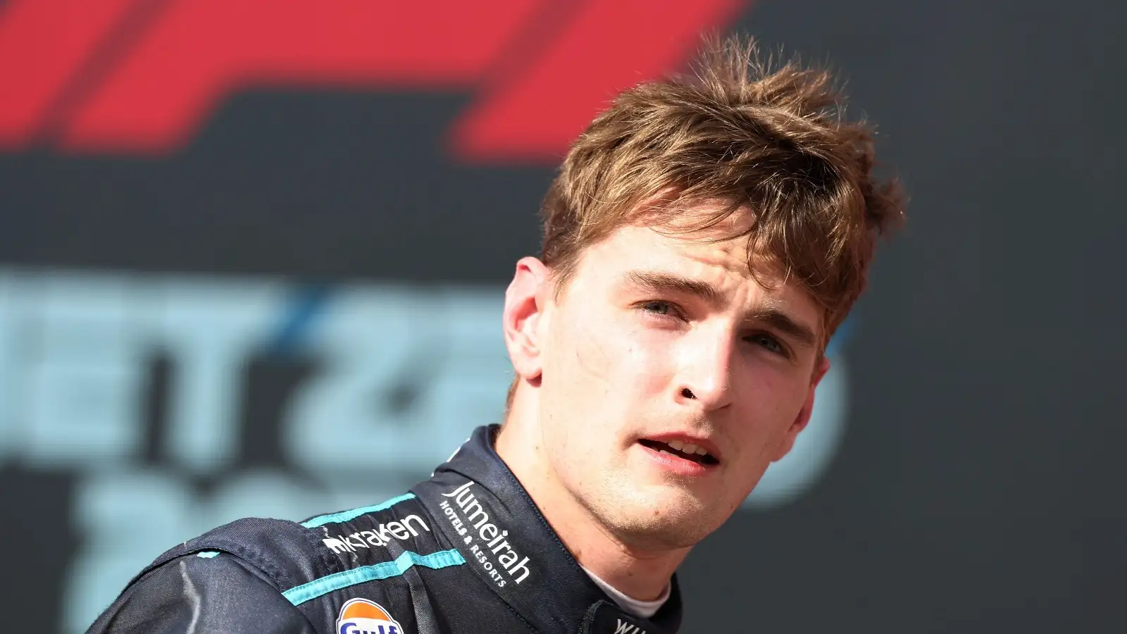 Williams driver Logan Sargeant looking forward with F1 branding backdrop.