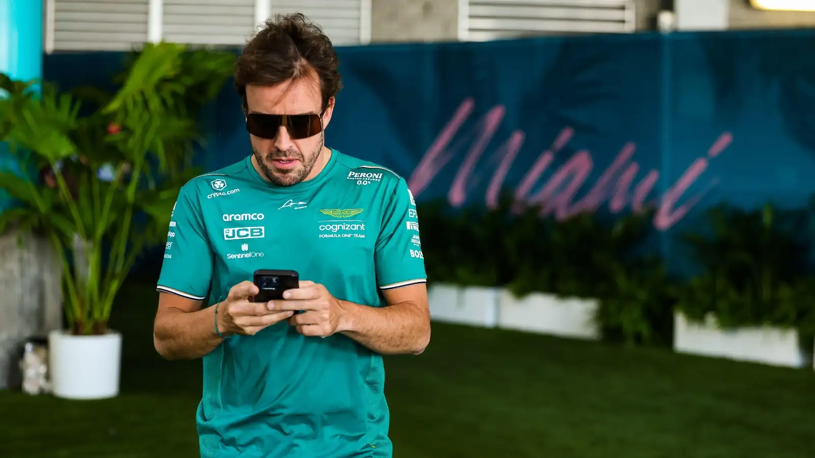 Aston Martin driver Fernando Alonso using his phone.