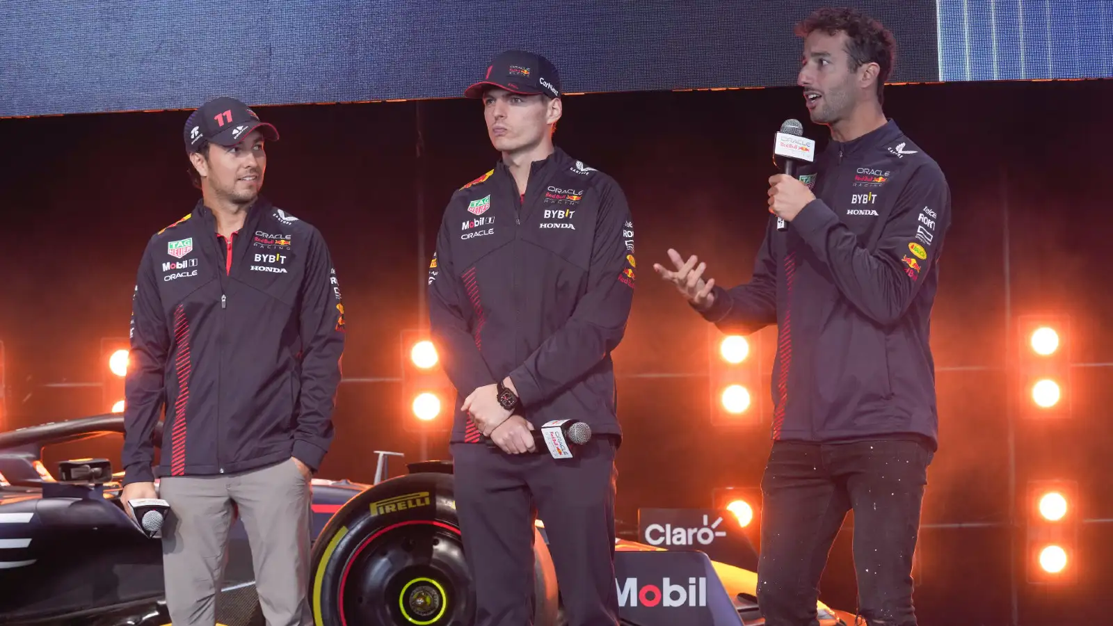 Red Bull F1 race drivers Sergio Perez and Max Verstappen look on as Red Bull reserve Daniel Ricciardo speaks at an event in early 2023.