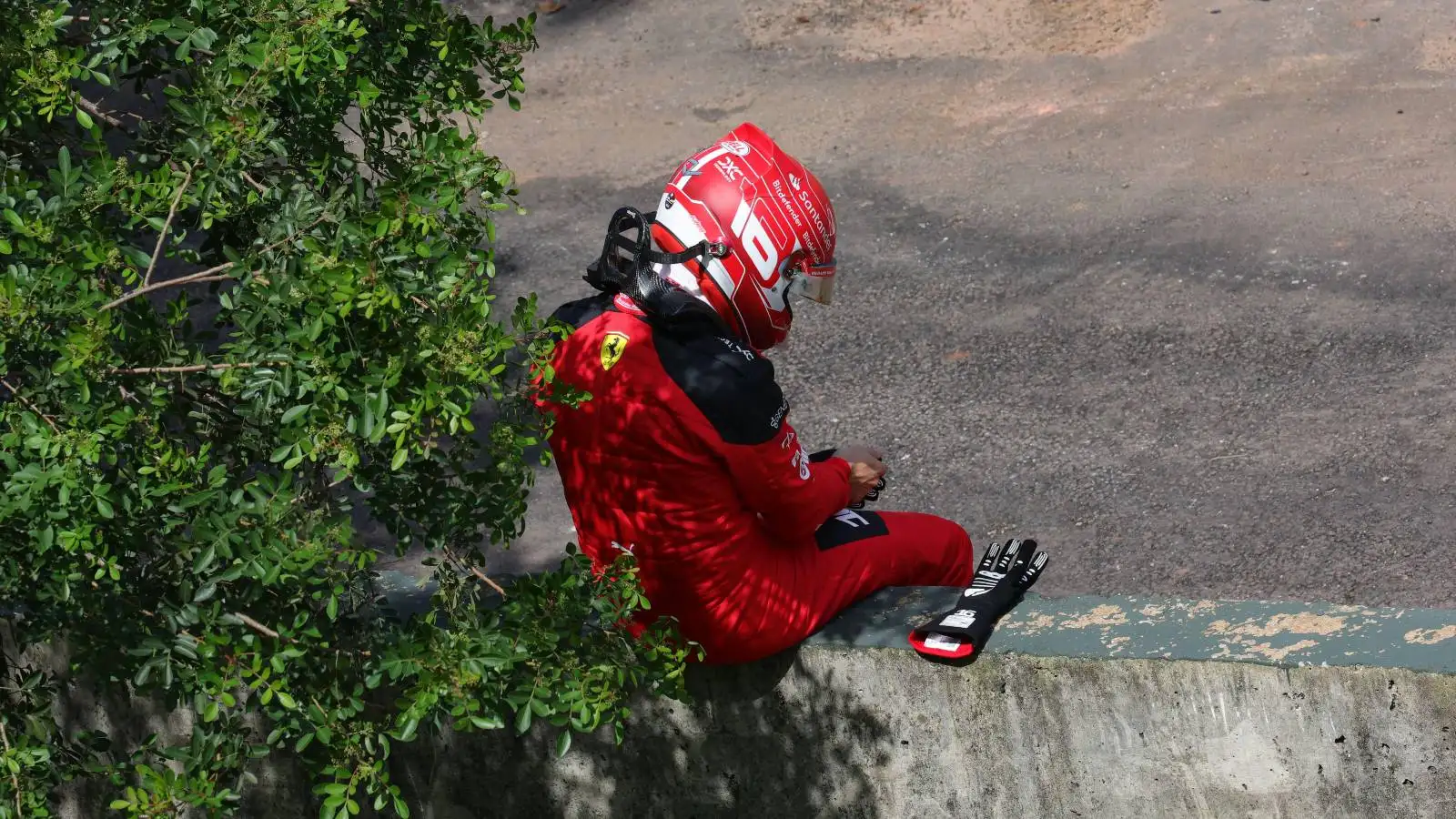 Disappointed Ferrari driver Charles Leclerc sitting on a wall after his Brazilian GP DNS.