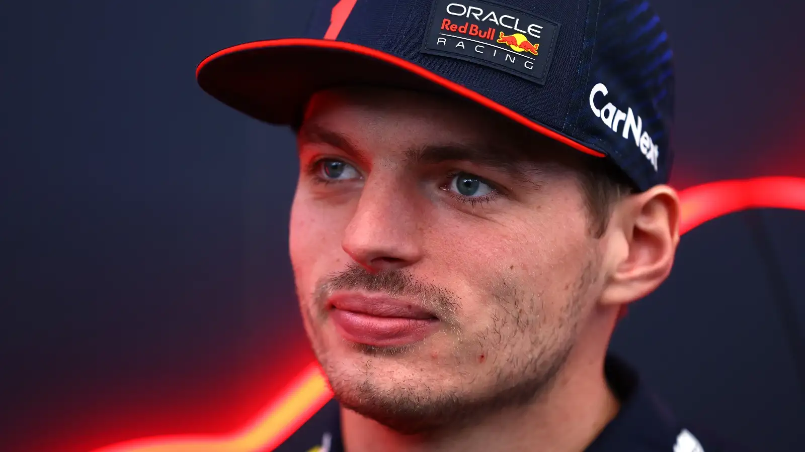 Max Verstappen looks past the camera with a slight smile.