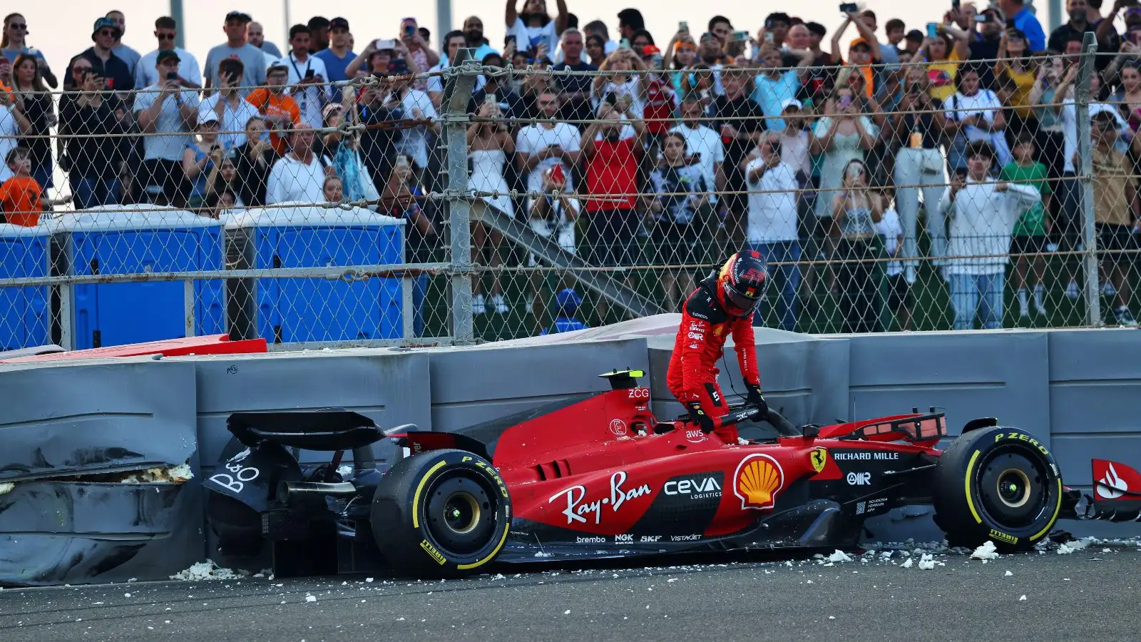 Carlos Sainz hopes out of his crashed Ferrari.