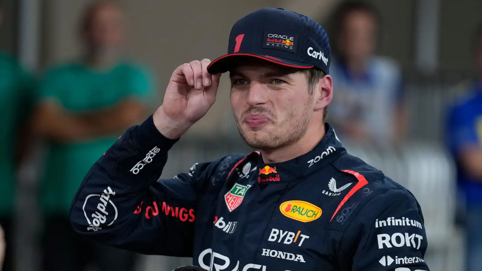 Red Bull driver Max Verstappen holds his cap wearing a very pleased smile.