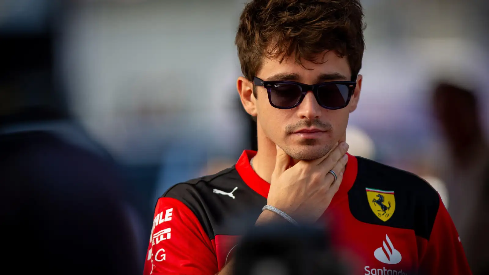 Ferrari F1 driver Charles Leclerc looking pensive in the paddock.