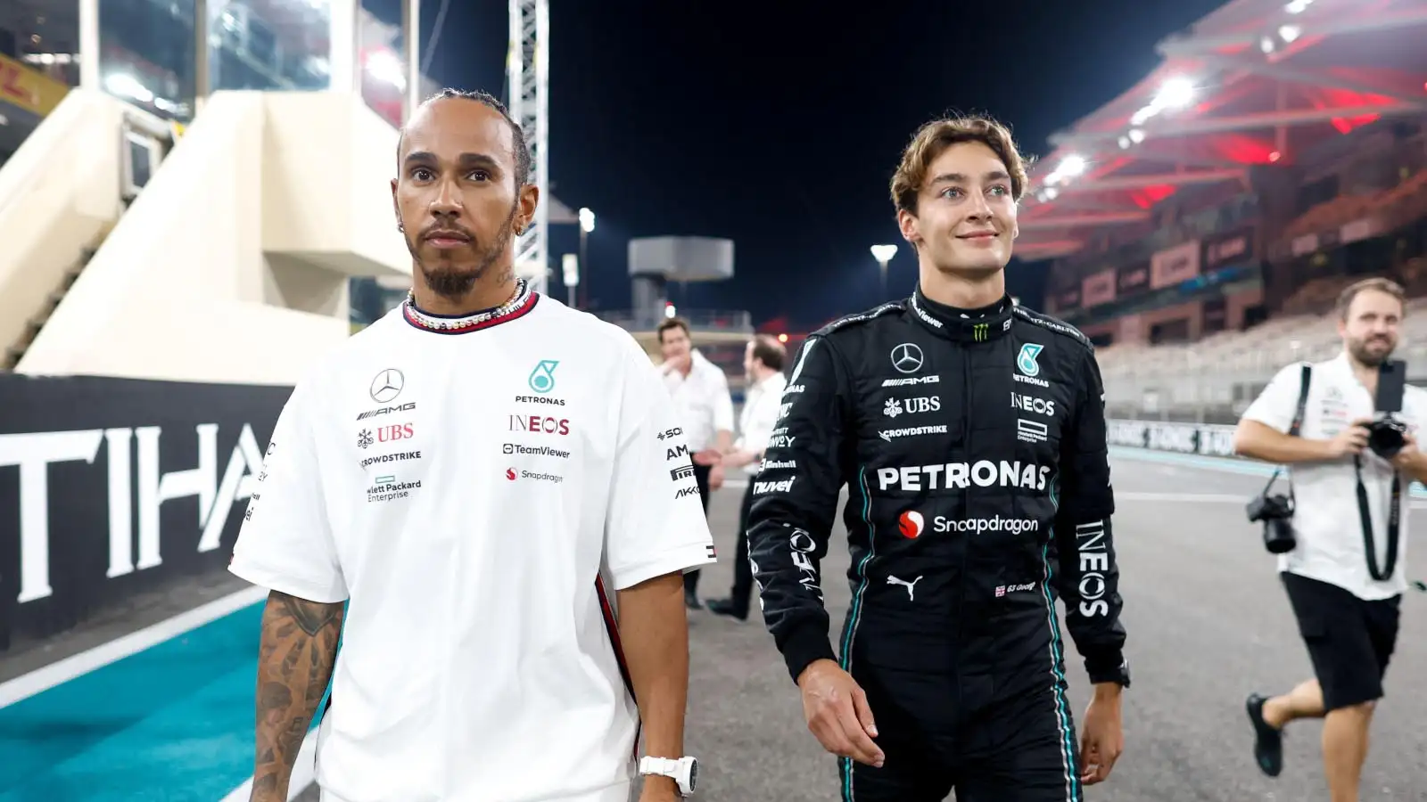Lewis Hamilton and George Russell walk on the grid.