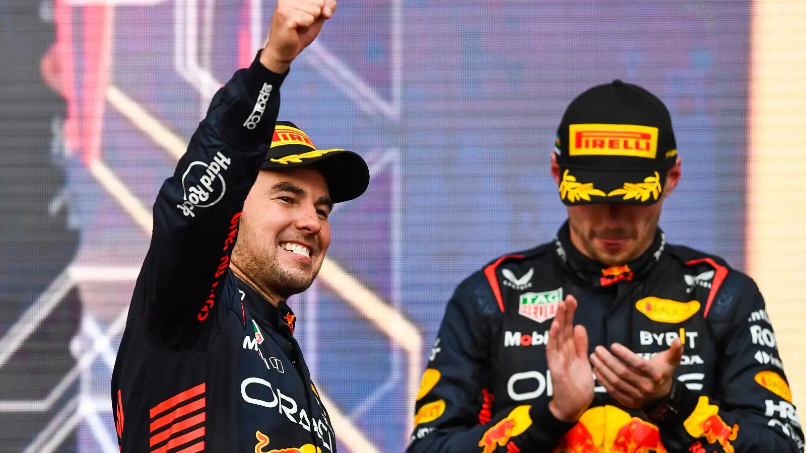 Max Verstappen looks down as Sergio Perez celebrates.
