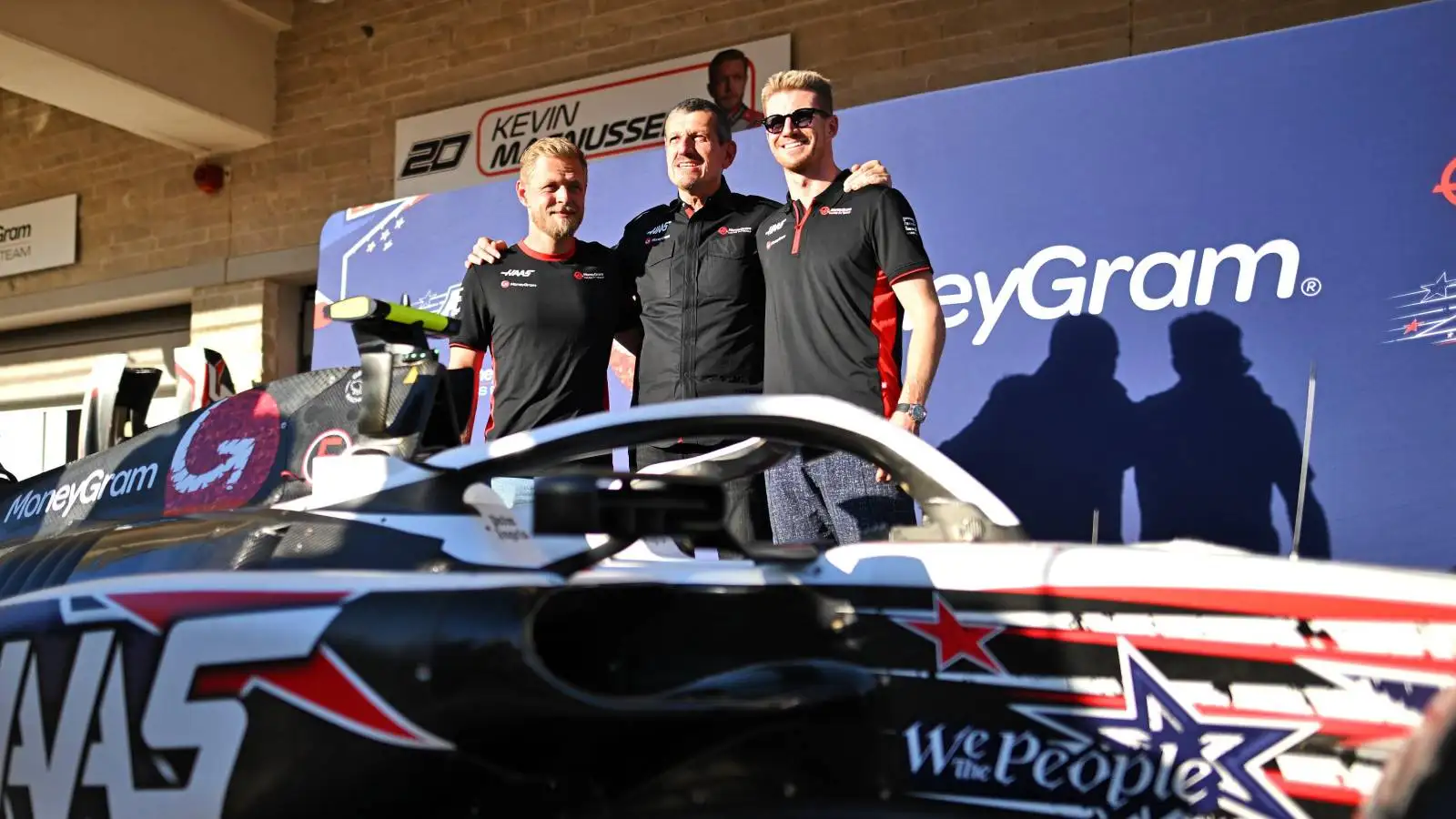 Haas drivers Kevin Magnussen and Nico Hulkenberg pose with former Haas team boss Guenther Steiner in front of the car.
