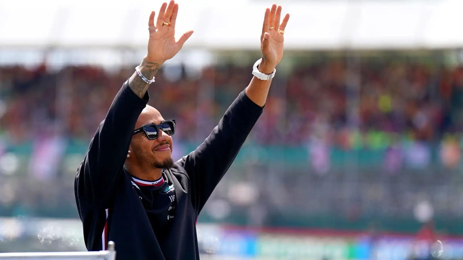 Lewis Hamilton raises his hands to the crowd.