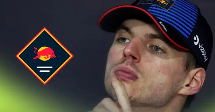 Max Verstappen looks deep in thought in a press conference with a prominent Red Bull logo alongside him